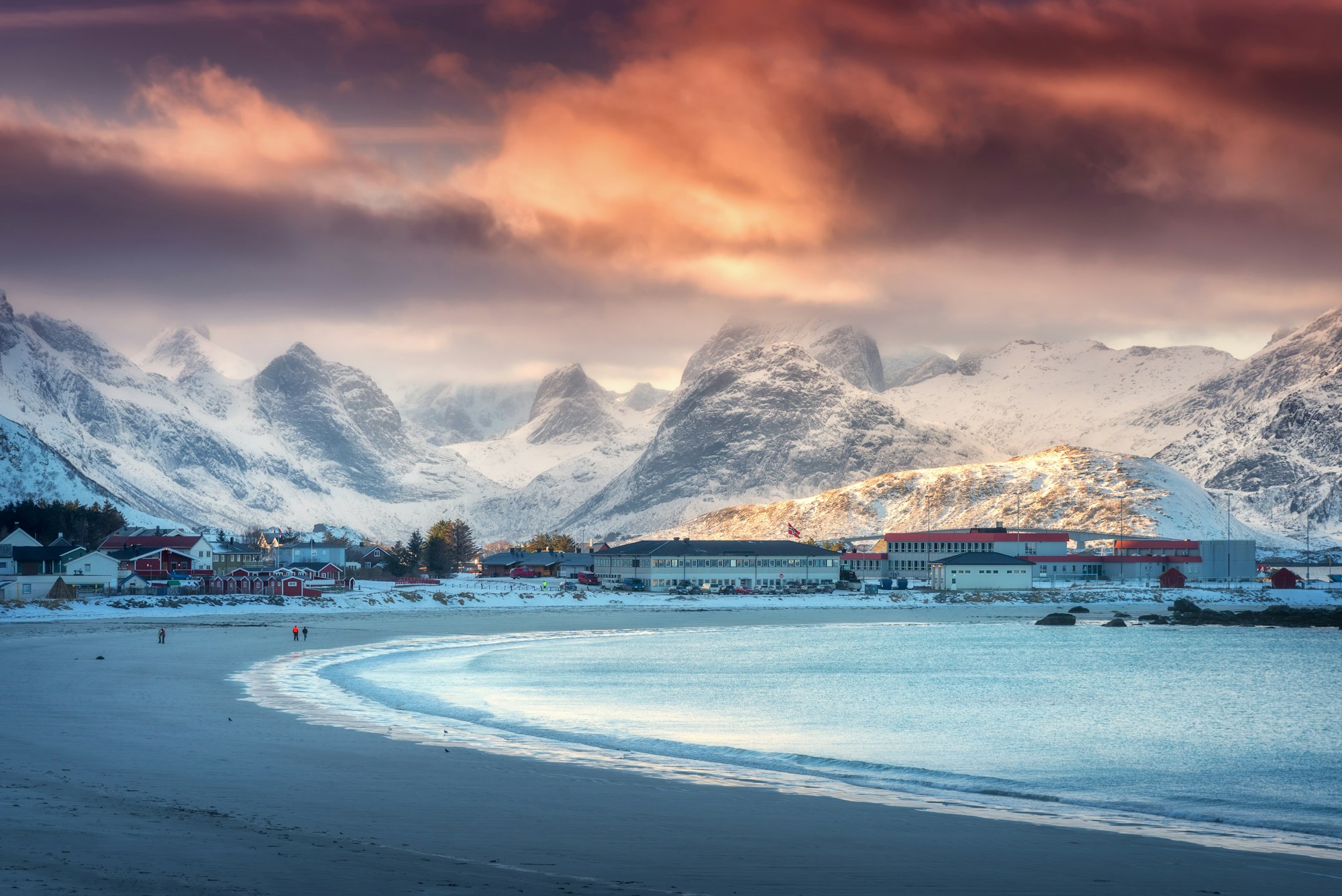 Beautiful arctic sandy beach, sea and snowy mountains at sunset