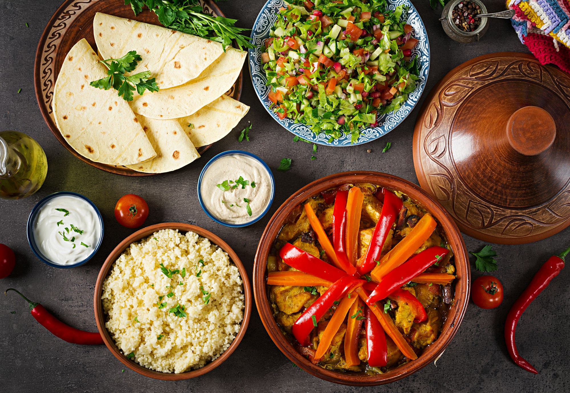 Moroccan food. Traditional tajine dishes, couscous and fresh salad on rustic wooden table.